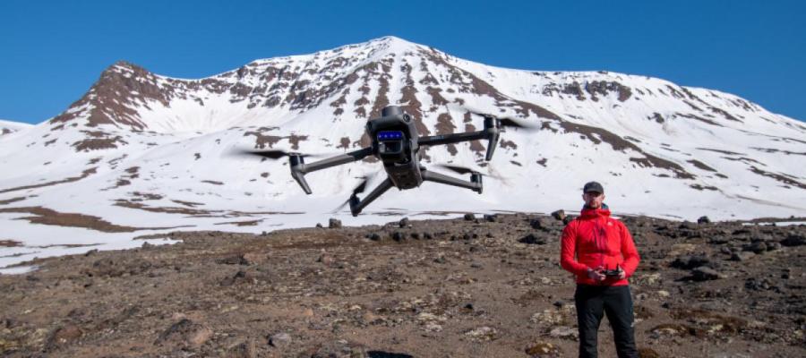 Mavic 3M drone in flight with snow covered mountain behind